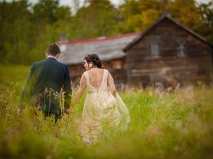 newlyweds walking to a cabin through tall grass