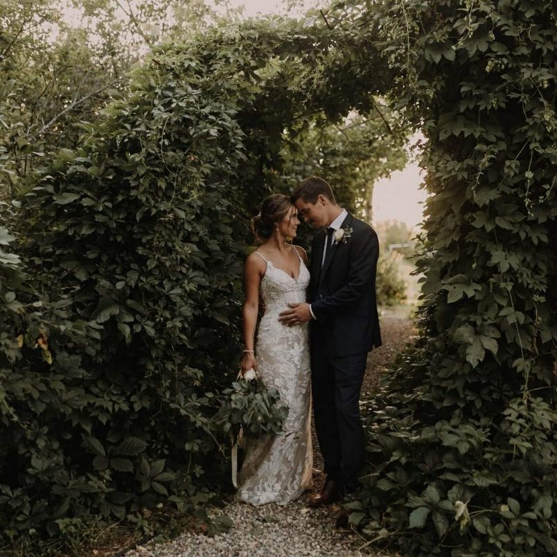 newlyweds standing with eachother surrounded by vine