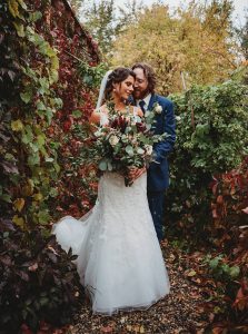 newlyweds holding each other surrounded by vines