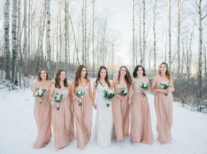 Bride with Bridesmaids in a row beside her outside in winter