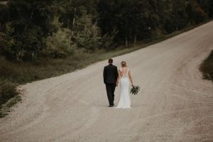 newlyweds walking down a dirt road