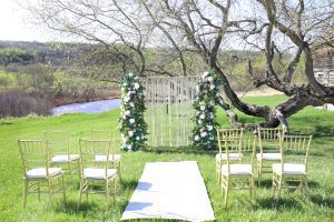 wedding altar with 4 chairs on each side of the aisle and a river in the background