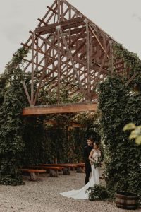 Newlyweds posing in front of a vine chapel