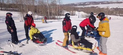 Instructors teaching people how to use Snow sleds