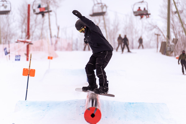 A snowboarder riding onto a rail.